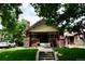 Charming brick home featuring a welcoming front porch, lush lawn, and mature trees at 723 Steele St, Denver, CO 80206