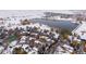 Aerial view of snow-covered community featuring a lake, trees, tennis court, and various homes at 4009 Wonderland Hill Ave, Boulder, CO 80304