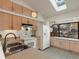 Bright kitchen featuring wood cabinets, white appliances, a skylight, and a large window with winter scenery at 4009 Wonderland Hill Ave, Boulder, CO 80304