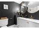 A stylish bathroom with black walls, contrasting white vanities, and elegant gold fixtures for a modern touch at 9565 W Lake Pl, Littleton, CO 80123