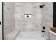 This bathroom features a bathtub with marble-style tiling, a built-in shelf, and a sleek black shower head at 9565 W Lake Pl, Littleton, CO 80123