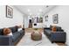 A modern living room featuring stylish sofas, a unique center ottoman, and open access to the kitchen and stairs at 9565 W Lake Pl, Littleton, CO 80123