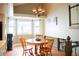 Cozy dining area with wood table, chairs, chandelier, and bright natural light from large window at 7961 Jared Way, Littleton, CO 80125