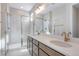 Bright bathroom featuring dual sinks, quartz countertop, and an enclosed glass shower at 16778 W 93Rd Pl, Arvada, CO 80007