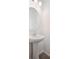 Stylish half bath with a pedestal sink, modern faucet, and a round mirror at 45922 Gentry Ave, Bennett, CO 80102