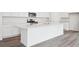 Modern kitchen with white cabinets, stainless steel appliances, and large island with quartz countertops at 45922 Gentry Ave, Bennett, CO 80102