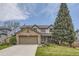 Charming two-story home boasts a stone-accented garage, lush lawn, and mature tree at 2420 S Ellis Ct, Lakewood, CO 80228