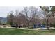 A community playground with swings and slides is nestled between mature trees with mountain views at 2420 S Ellis Ct, Lakewood, CO 80228