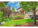 Beautifully landscaped backyard with a brick privacy screen, lush lawn, mature trees and a BBQ grill at 9244 E 37Th Ave, Denver, CO 80238