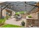 Covered patio with outdoor dining area, brick retaining wall, landscaping, and grill area at 9244 E 37Th Ave, Denver, CO 80238