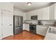 Well-lit kitchen featuring stainless steel appliances, white cabinetry, and hardwood floors at 3912 Miners Candle Pl, Castle Rock, CO 80109