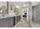 Bathroom featuring double sinks, dark cabinets, tile floors, and a tiled shower with glass door at 16680 Stroilway St, Hudson, CO 80642