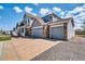 Side view of house showing a three-car garage, brick accents, and a well-manicured lawn at 16680 Stroilway St, Hudson, CO 80642