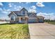 Charming two-story home featuring a welcoming front porch and three-car garage on a sunny day at 16680 Stroilway St, Hudson, CO 80642