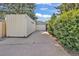A detached garage with modern doors is accessible via a concrete driveway and is surrounded by a privacy fence and lush greenery at 1830 Zang St, Golden, CO 80401