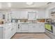 Bright kitchen features white cabinetry, tile backsplash, stainless steel appliances, and wood-look flooring at 1830 Zang St, Golden, CO 80401