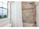 Clean bathroom featuring stone tile, shower-tub combo, and bright window at 10783 Skydance Dr, Highlands Ranch, CO 80126