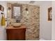 Stylish powder room featuring a unique stone wall, vessel sink, and decorative mirror at 1688 Pine Valley Rd, Evergreen, CO 80439