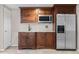 Basement wet bar with dark wood cabinets, granite countertops, microwave, sink, and stainless steel fridge at 3418 Elk Ct, Broomfield, CO 80020