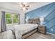 Stylish bedroom with a geometric accent wall, ceiling fan, and a large window at 9519 W Coal Mine Ave # F, Littleton, CO 80123