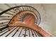 Overhead view of a curved staircase with decorative iron railing, carpet on the stairs and hardwood landing on the main level at 4605 Tierra Alta Dr, Castle Rock, CO 80104