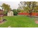 Large, green backyard featuring a storage shed, mature trees, and wood fence at 9642 Meade Ct, Westminster, CO 80031