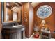 Charming powder room with decorative mirror and unique round window, adding architectural interest at 10061 Bluffmont Ct, Lone Tree, CO 80124