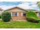 Charming brick townhome exterior features green bushes, a well-maintained lawn, and bright white window shutters at 9824 Lane St, Thornton, CO 80260