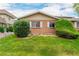 Charming exterior of a brick townhome with green shrubs, a well-maintained lawn, and bright white window shutters at 9824 Lane St, Thornton, CO 80260