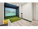 Home golf simulator room complete with a large screen, artificial turf, and putting green for practice at 10441 Carriage Club Dr, Lone Tree, CO 80124