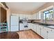 Bright kitchen featuring white appliances, wood-look floors, and ample counter space for food prep at 12995 W Chenango Ave, Morrison, CO 80465