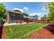Wide view of a backyard featuring green grass, trees, rock, a deck, and a fence at 12908 Hudson St, Thornton, CO 80241