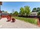 Landscaped backyard featuring a well-maintained lawn, fire pit, seating, deck, and wooden fence at 12908 Hudson St, Thornton, CO 80241