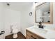 Modern bathroom with a wood vanity, a white countertop, and a framed mirror, complemented by a toilet at 20112 E Grand Pl, Aurora, CO 80015