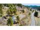 Aerial view of the property, neighboring buildings, and roadside with a mountainous backdrop at 20951 Pleasant Park Rd, Conifer, CO 80433