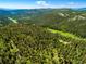 An aerial view of a lush, green landscape with rolling hills covered in dense forest and distant mountain views at 20951 Pleasant Park Rd, Conifer, CO 80433