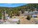 An aerial view of the home, neighboring buildings, and wooded, mountainous landscape at 20951 Pleasant Park Rd, Conifer, CO 80433