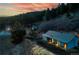 A picturesque barn illuminated at dusk, set against a tranquil woodland backdrop at 20951 Pleasant Park Rd, Conifer, CO 80433