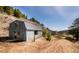 Exterior view of the property with a wooden outbuilding and dirt road on a sunny day at 20951 Pleasant Park Rd, Conifer, CO 80433