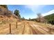 Dirt road on a sunny day with green trees in the background and a clear blue sky at 20951 Pleasant Park Rd, Conifer, CO 80433