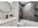 Modern bathroom with a bathtub, shower featuring gray marble-style tile, and sleek black fixtures and finishes at 8356 W 87Th Dr # A, Arvada, CO 80005