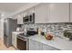 Modern kitchen featuring stainless steel appliances, gray cabinets, and stylish backsplash at 8356 W 87Th Dr # A, Arvada, CO 80005