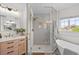Bright bathroom showcasing glass shower with gold fixtures, tub, and a stylish wood vanity at 10802 W Indore Dr, Littleton, CO 80127