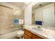 Bathroom features a vanity with a large mirror and combined shower and tub with glass doors at 9400 E Iliff Ave # 88, Denver, CO 80231