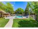 Community pool with seating, surrounded by mature trees and landscaped grounds on a sunny day at 9400 E Iliff Ave # 88, Denver, CO 80231