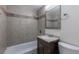 Well-lit bathroom with tiled walls, a bathtub, a wooden vanity, and modern fixtures at 6176 Ammons St, Arvada, CO 80004