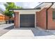 Attached garage featuring a dark door with concrete driveway and red brick at 6176 Ammons St, Arvada, CO 80004