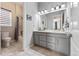 Bathroom featuring tile floors, grey vanity, toilet, shower and modern vanity lighting at 17860 Calendula Dr, Parker, CO 80134