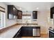Stylish kitchen with granite countertops, dark cabinetry, stainless steel dishwasher, and tile backsplash at 4780 E Montana Pl, Denver, CO 80222