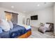 Modern bedroom with wood-look floors, sliding barn door, mounted tv, and comfy chaise lounge at 817 Backcountry Ln, Highlands Ranch, CO 80126